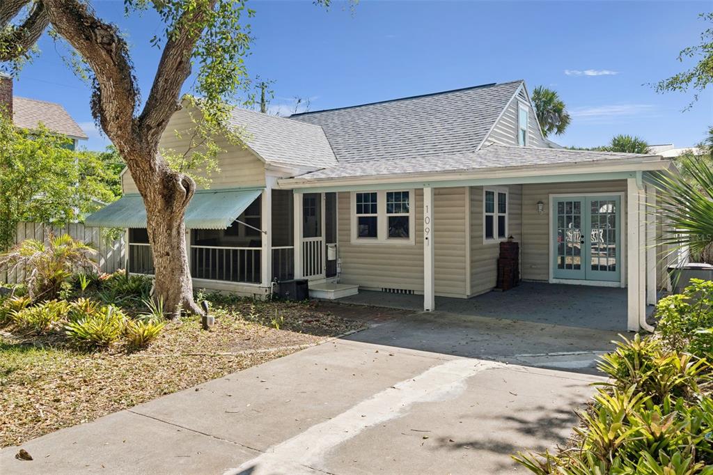 A one-story house with light siding, a covered porch, a carport, and a large tree — 109 N PENINSULA AVENUE, NEW SMYRNA BEACH, FL