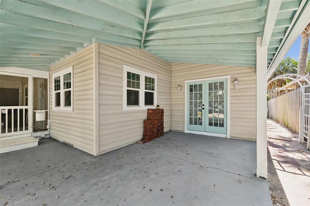 A covered concrete patio features beige siding, a light blue ceiling, and French doors — 109 N PENINSULA AVENUE, NEW SMYRNA BEACH, FL
