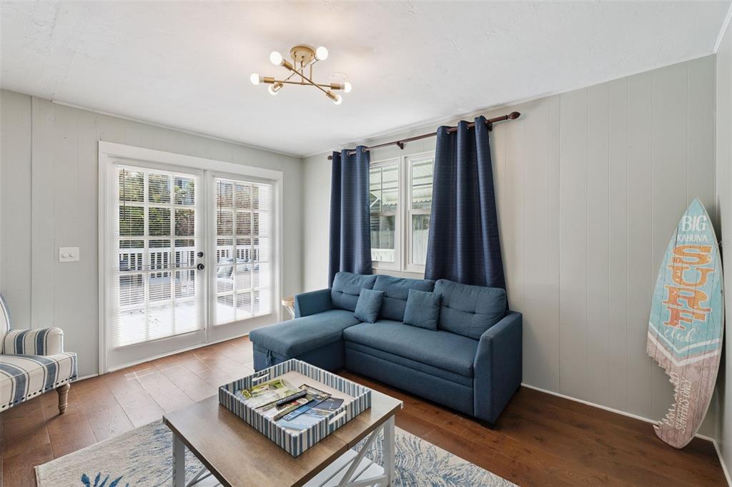 A living room features a blue sectional sofa, a coffee table, and a surfboard decoration — 109 N PENINSULA AVENUE, NEW SMYRNA BEACH, FL