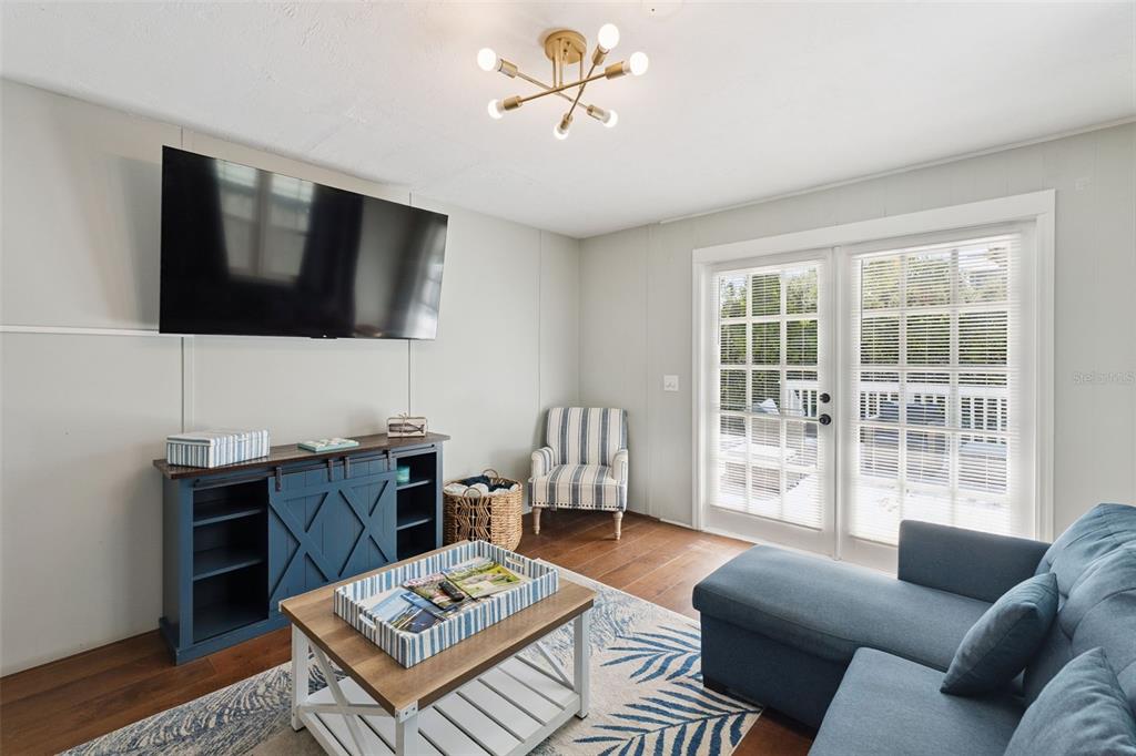 A living room features a blue media console, a sectional sofa, and French doors — 109 N PENINSULA AVENUE, NEW SMYRNA BEACH, FL