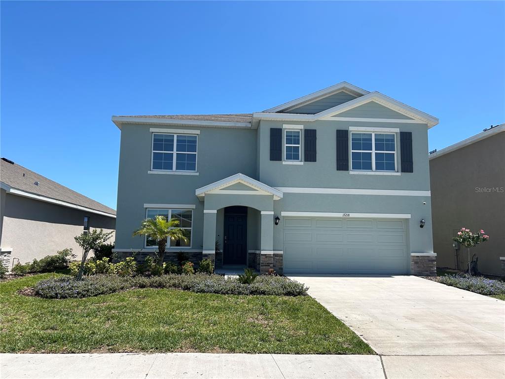 A two-story house with light blue stucco siding, a two-car garage, and a front porch — 17218 RESERVA DRIVE, BRADENTON, FL