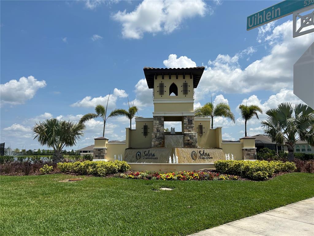 A decorative stone and stucco monument sign with a fountain marks the entrance to Solera — 17218 RESERVA DRIVE, BRADENTON, FL