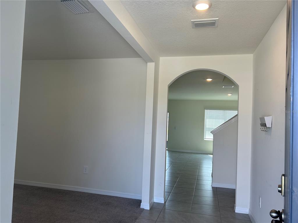 An interior view shows a carpeted room leading through an arched doorway to a tiled area — 17218 RESERVA DRIVE, BRADENTON, FL