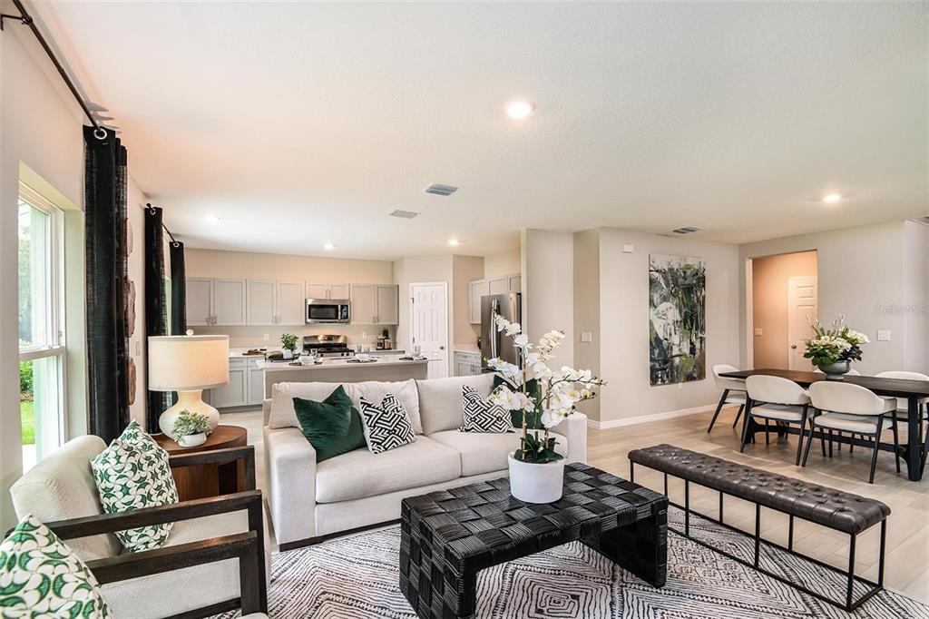 An open-concept living room and kitchen featuring light-colored cabinetry, a sofa, and dining area — 36645 SAGEMOOR DRIVE, ZEPHYRHILLS, FL