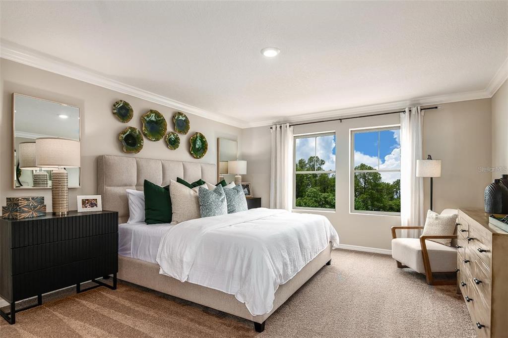 A bedroom features a beige upholstered headboard, green and patterned pillows, and two large windows — 36645 SAGEMOOR DRIVE, ZEPHYRHILLS, FL