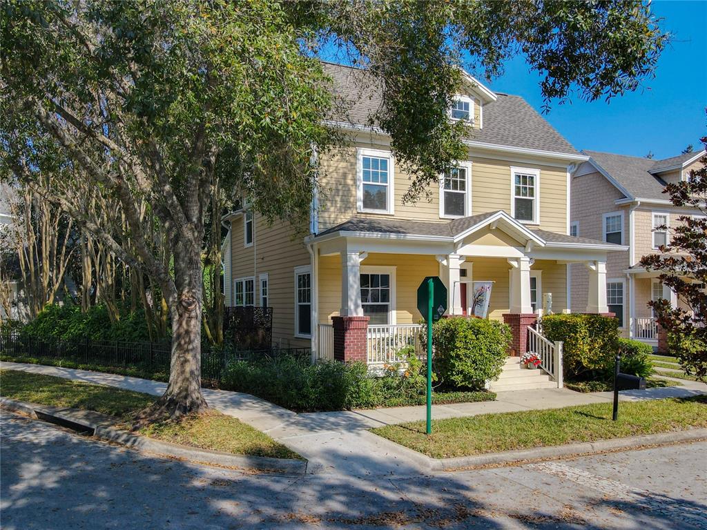 A yellow two-story house with a front porch and brick columns stands on a corner — 1101 BANKS ROSE COURT, CELEBRATION, FL