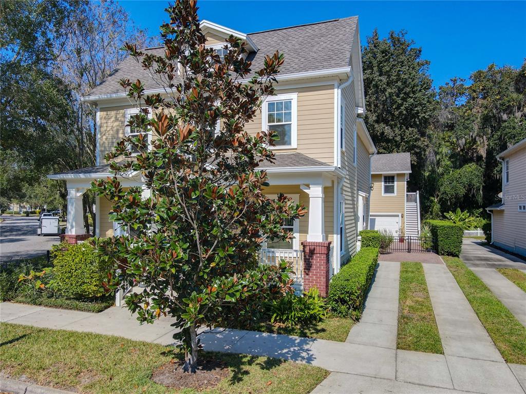 A two-story tan house with a front porch, a magnolia tree, and a detached garage — 1101 BANKS ROSE COURT, CELEBRATION, FL