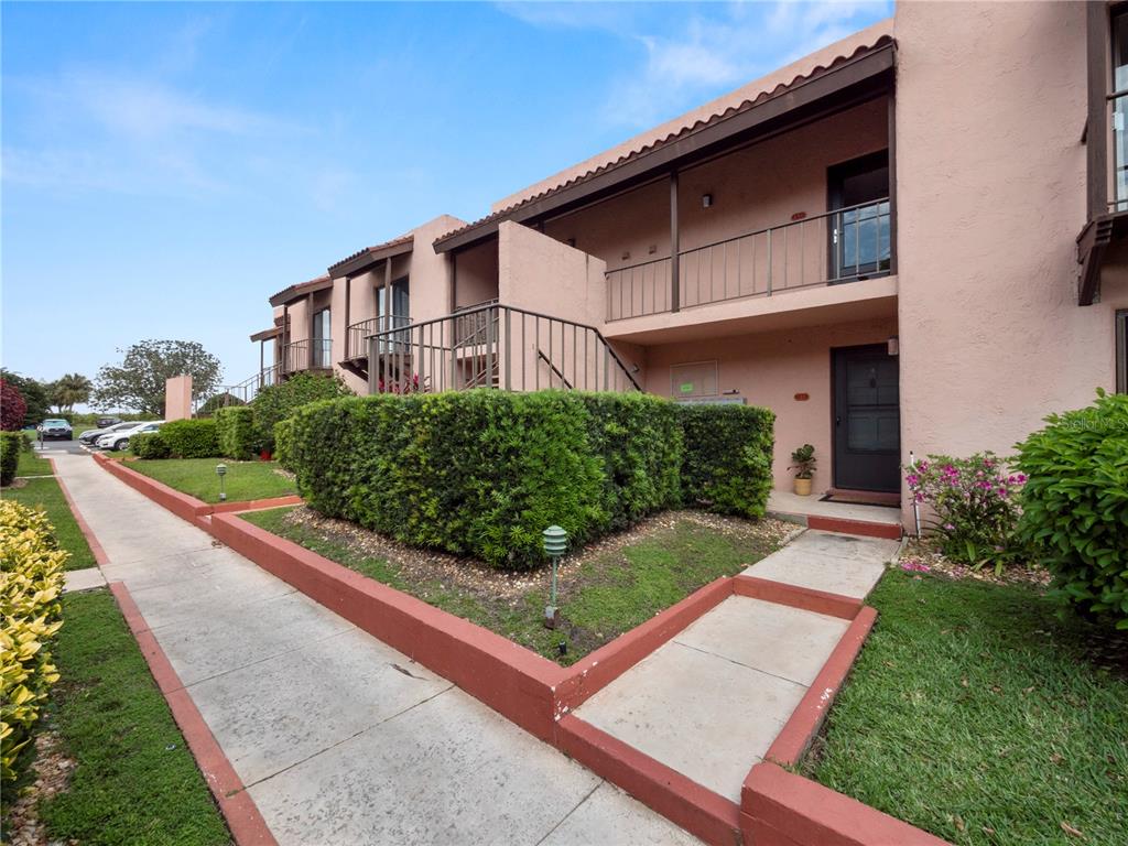 A two-story pink stucco apartment building features exterior staircases, balconies, and manicured landscaping — 230 LA CASA UNIT 230, LAKE WALES, FL