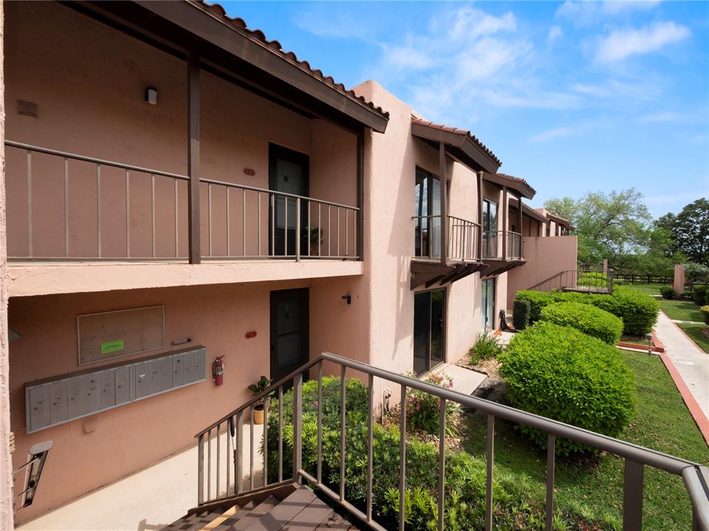 An exterior view of a two-story apartment building with stucco walls, balconies, and mailboxes — 230 LA CASA UNIT 230, LAKE WALES, FL