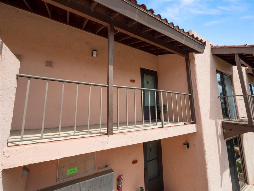 An exterior view of a two-story stucco building with balconies and metal railings — 230 LA CASA UNIT 230, LAKE WALES, FL