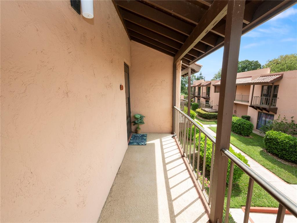 An outdoor balcony with a concrete floor, metal railing, and a view of neighboring buildings — 230 LA CASA UNIT 230, LAKE WALES, FL