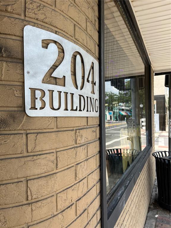 A metal sign reading 204 BUILDING is mounted on a tan brick exterior wall — 204 W UNIVERSITY AVENUE UNIT 8B, GAINESVILLE, FL