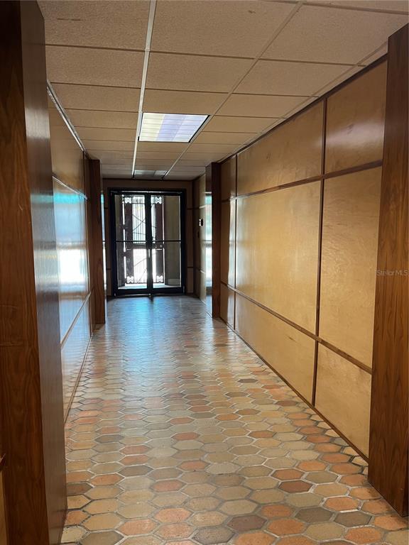 A hallway with wood-paneled walls, a drop ceiling, and a hexagonal tile floor — 204 W UNIVERSITY AVENUE UNIT 8B, GAINESVILLE, FL