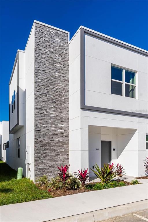 A modern two-story townhouse exterior features white paneling, gray stone veneer, and a recessed entrance — 392 FAMAGUSTA DRIVE, DAVENPORT, FL