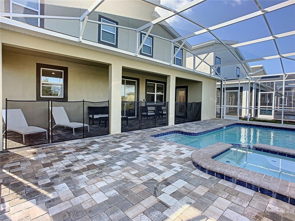 A patio with a pool, spa, and mesh safety fence under a screened enclosure — 8841 CRUDEN BAY COURT, DAVENPORT, FL