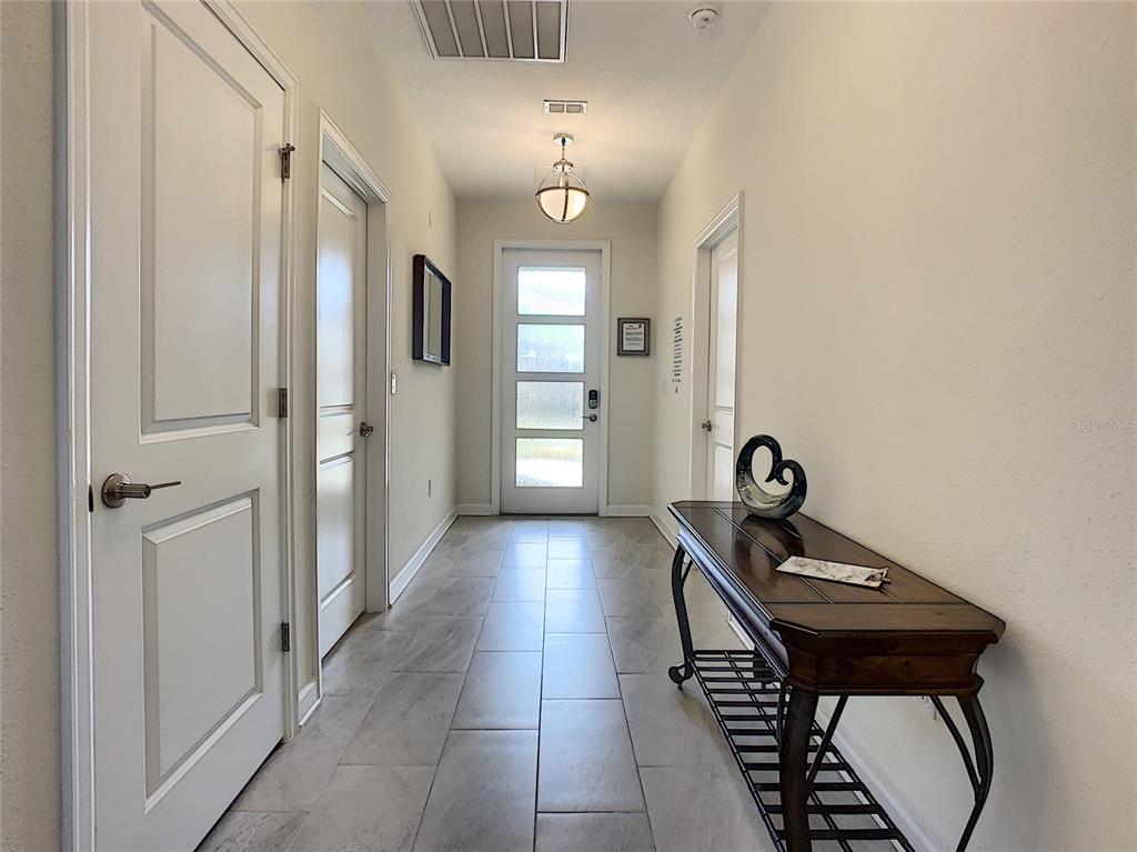 A bright entryway features light tile flooring, a wooden console table, and a glass-paneled front door — 8841 CRUDEN BAY COURT, DAVENPORT, FL