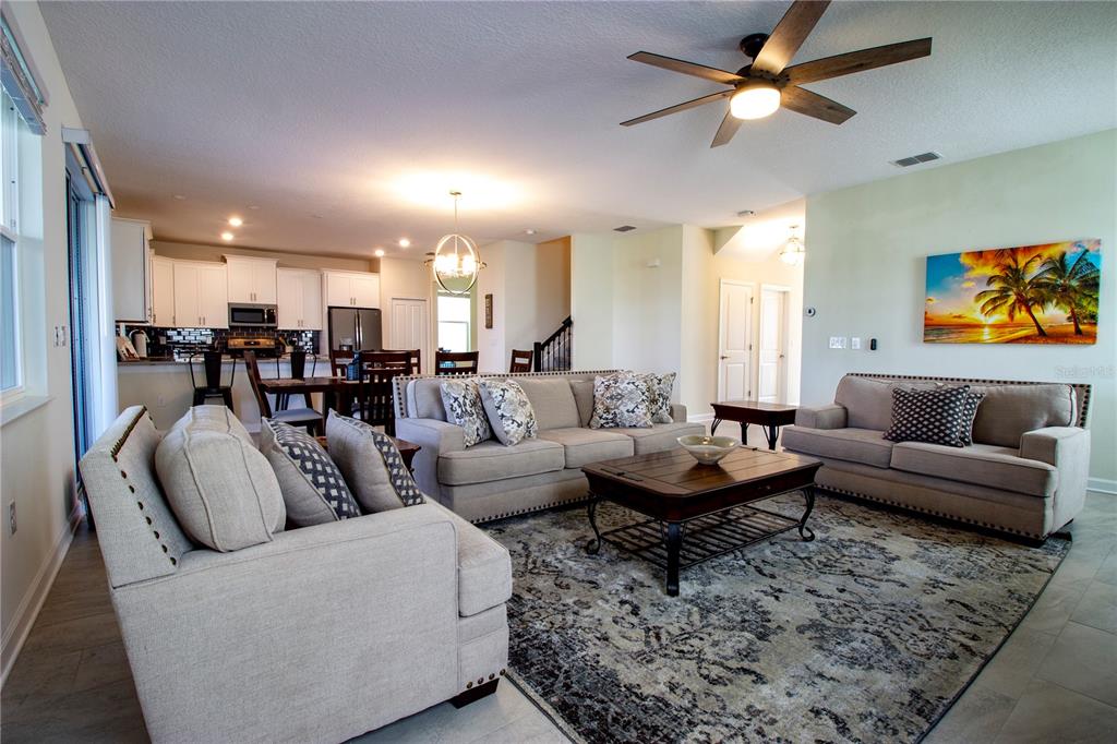 A living room with light-colored sofas, a wooden coffee table, and an open-concept kitchen — 8841 CRUDEN BAY COURT, DAVENPORT, FL