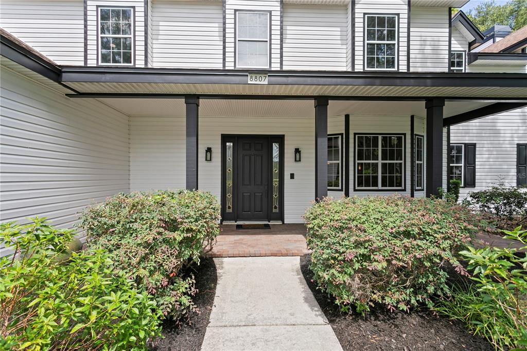A front entrance features a dark door with sidelights, a covered porch, and landscaping — 8807 EAGLE WATCH DRIVE, RIVERVIEW, FL