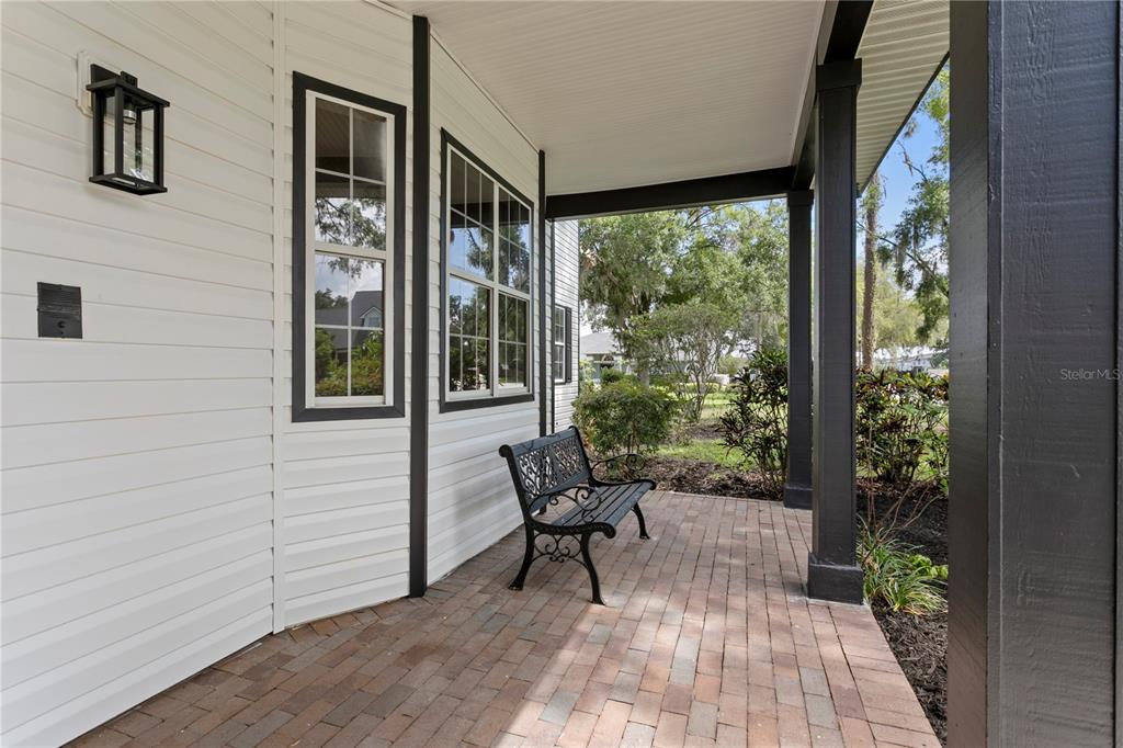 A covered porch features a brick floor, a black metal bench, and white siding — 8807 EAGLE WATCH DRIVE, RIVERVIEW, FL
