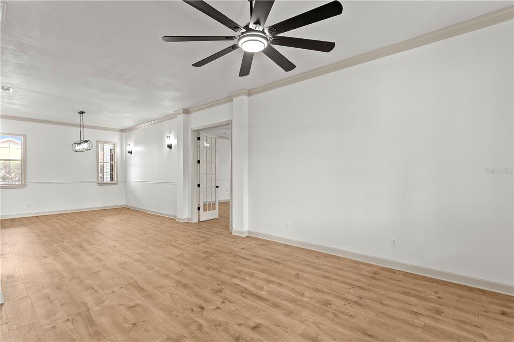 An empty room with light wood-look flooring, white walls, and a dark ceiling fan — 8807 EAGLE WATCH DRIVE, RIVERVIEW, FL
