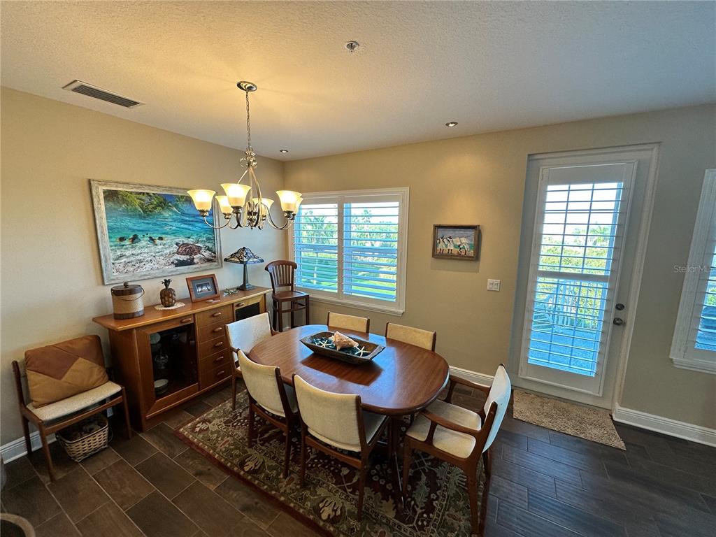 A dining room features a wooden table, six chairs, a sideboard, and a glass door — 7740 34TH AVE W UNIT 202, BRADENTON, FL
