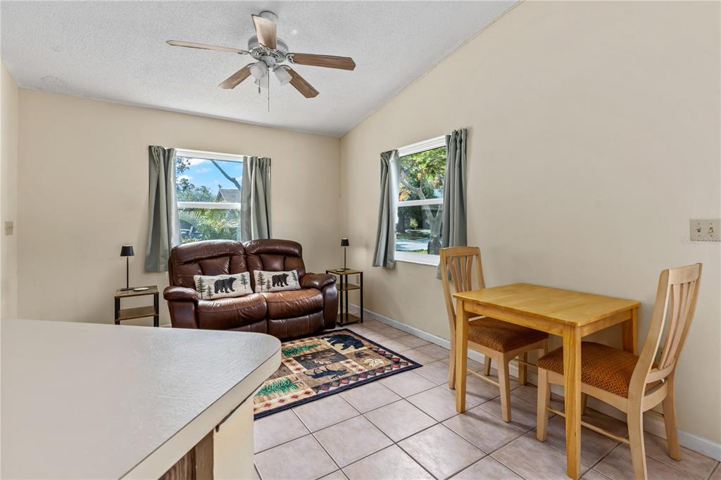 A room with tile flooring, a brown leather loveseat, a dining table, and ceiling fan — 5723 DEER HOLLOW TRAIL, SARASOTA, FL