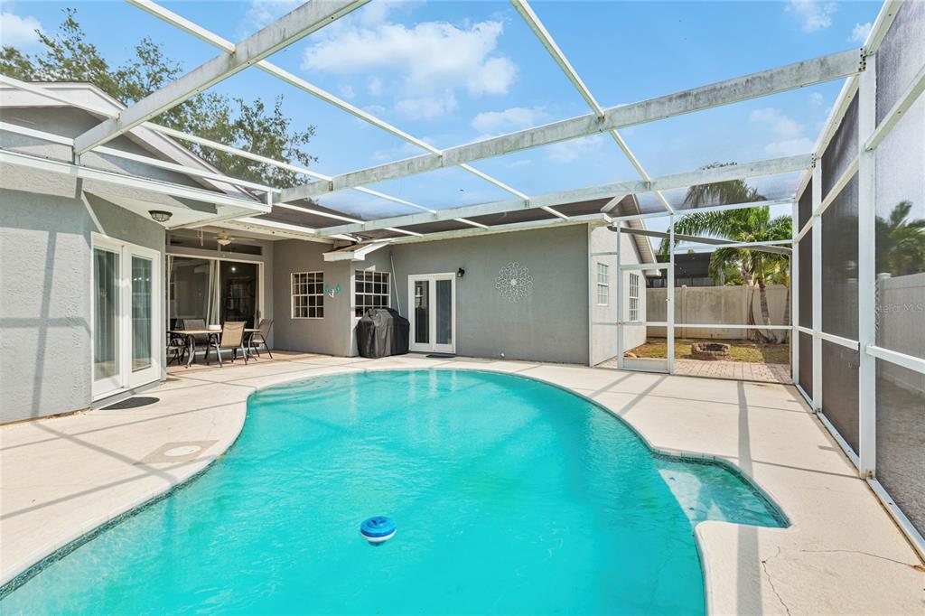 A backyard swimming pool enclosed by a screened lanai with a patio and house exterior — 1690 WINNERS CIRCLE, TARPON SPRINGS, FL