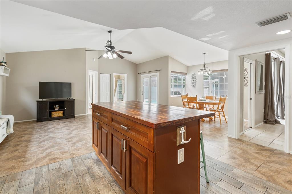 A kitchen island with a wood countertop sits in an open-concept room with tile flooring — 1690 WINNERS CIRCLE, TARPON SPRINGS, FL