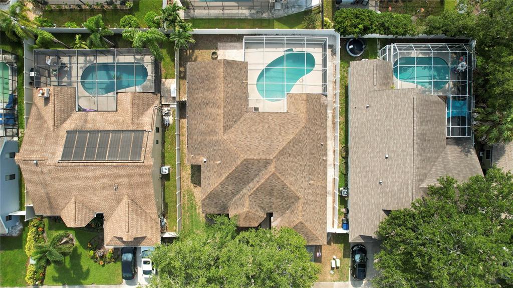 An aerial view shows three adjacent houses with swimming pools and screened-in lanais — 1690 WINNERS CIRCLE, TARPON SPRINGS, FL