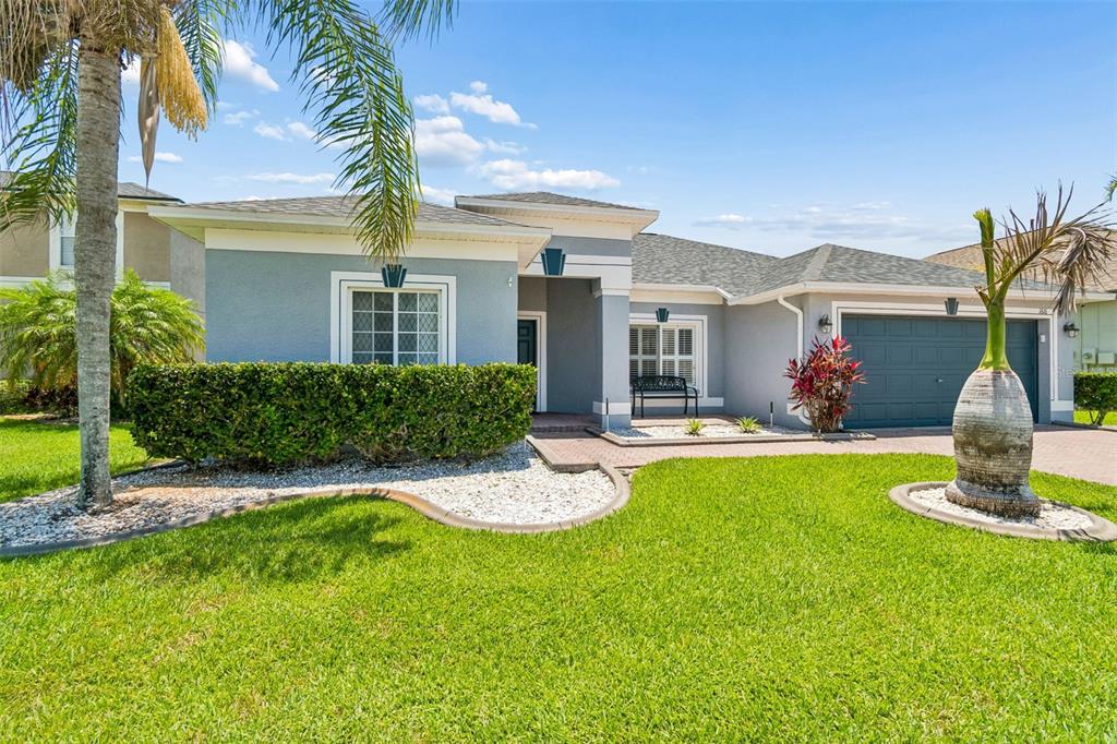 A single-story house with a blue exterior, a two-car garage, and a landscaped front yard — 1616 REGAL MIST LOOP, TRINITY, FL
