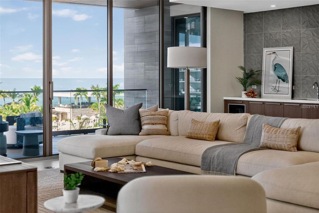 A modern living room features a large beige sectional sofa, a coffee table, and balcony views — 1591 GULF OF MEXICO DRIVE UNIT 410, LONGBOAT KEY, FL