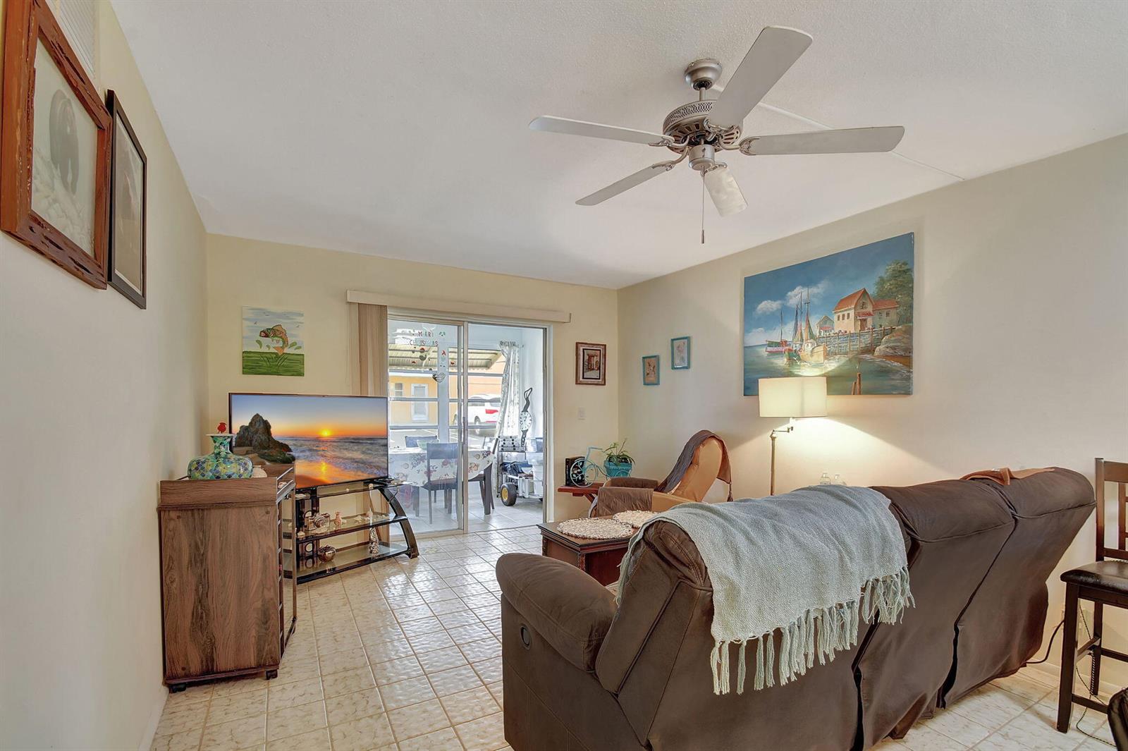A living room with tile flooring, a ceiling fan, a sofa, and a sliding glass door — 2121 NE 1st Court # 105, Boynton Beach FL 33435, BOYNTON BEACH, FL