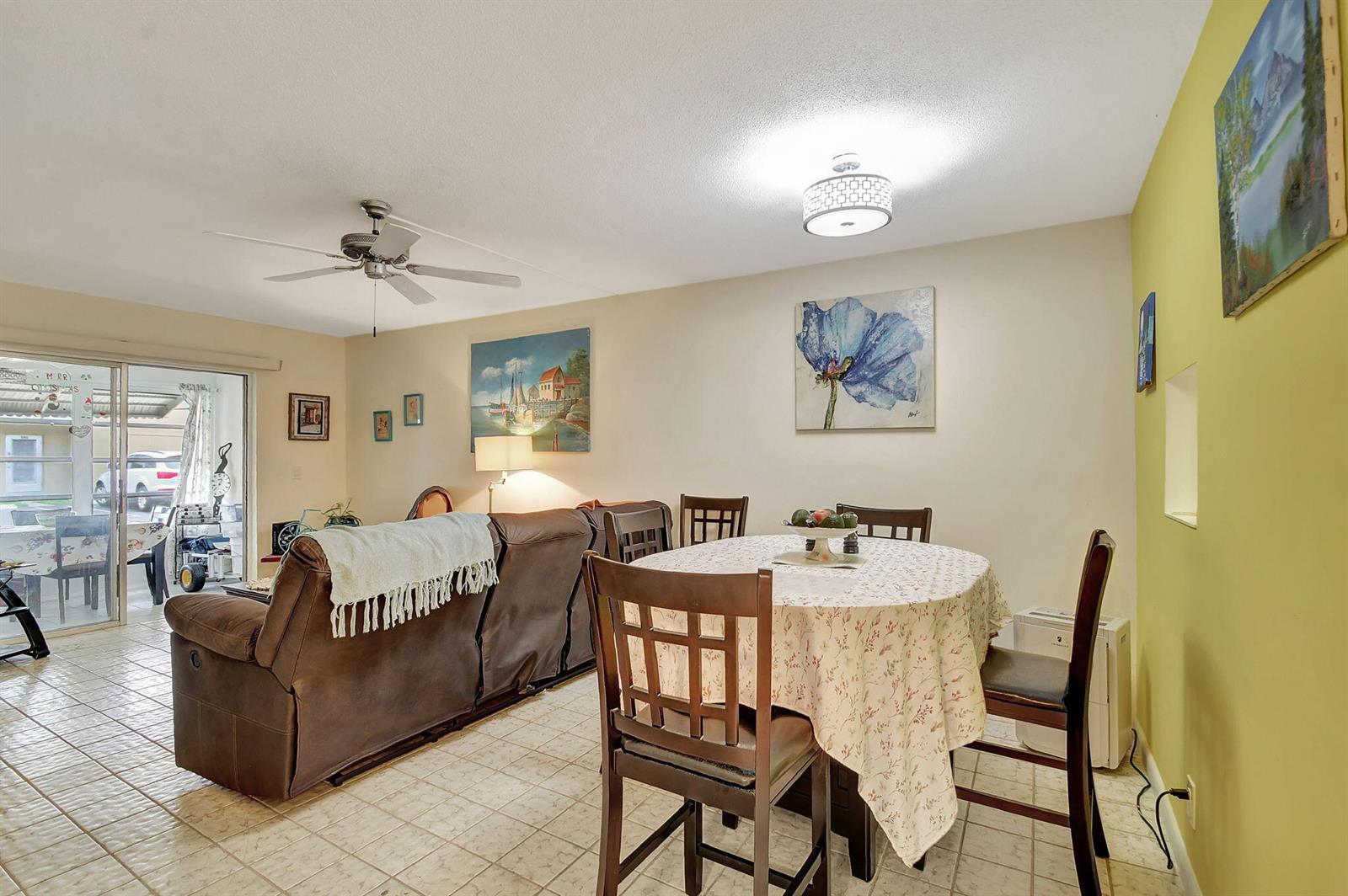 A living and dining area with tile floors, a brown sofa, and a round table — 2121 NE 1st Court # 105, Boynton Beach FL 33435, BOYNTON BEACH, FL