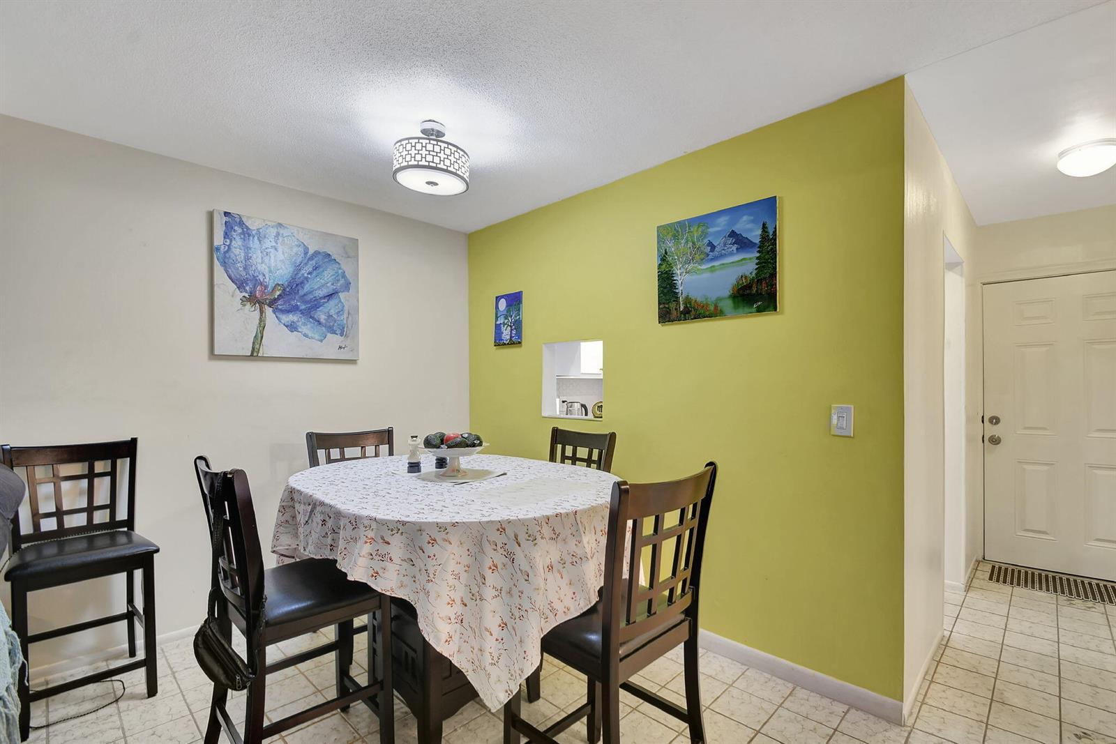 A dining area features a round table, four chairs, and a lime green accent wall — 2121 NE 1st Court # 105, Boynton Beach FL 33435, BOYNTON BEACH, FL