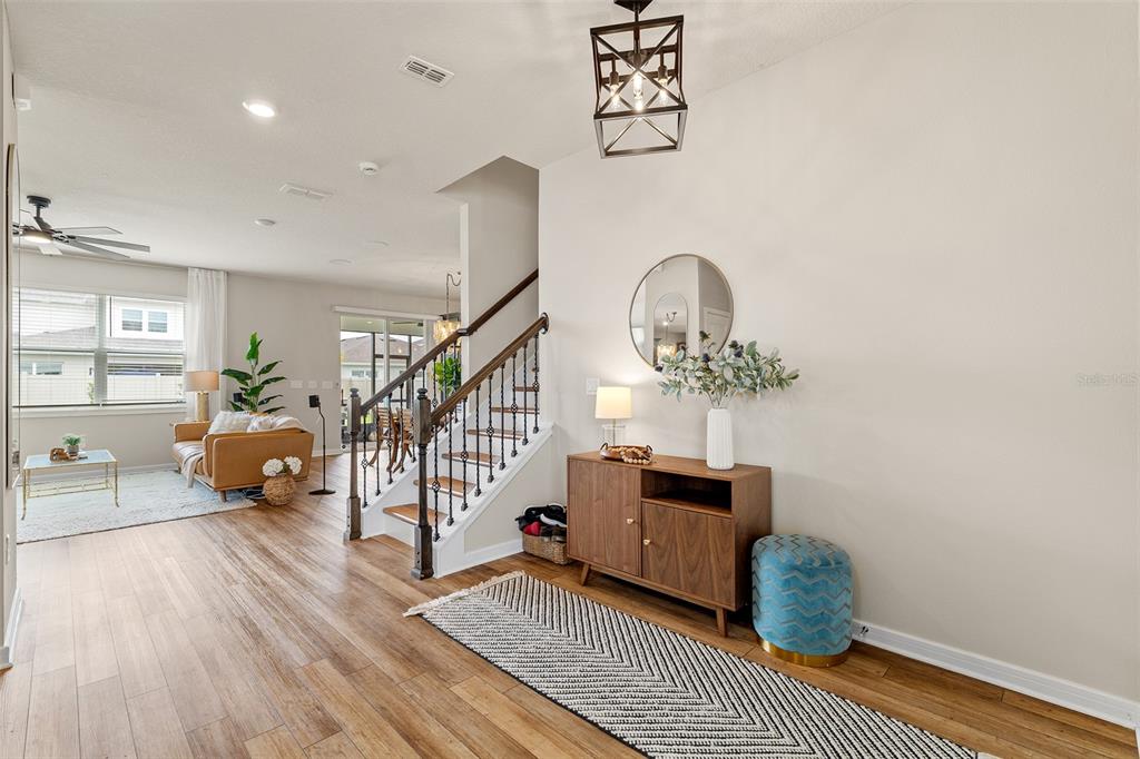 A bright entryway features a wooden staircase, a console table, and light wood flooring — 1444 GRAND PALM DRIVE, ORLANDO, FL