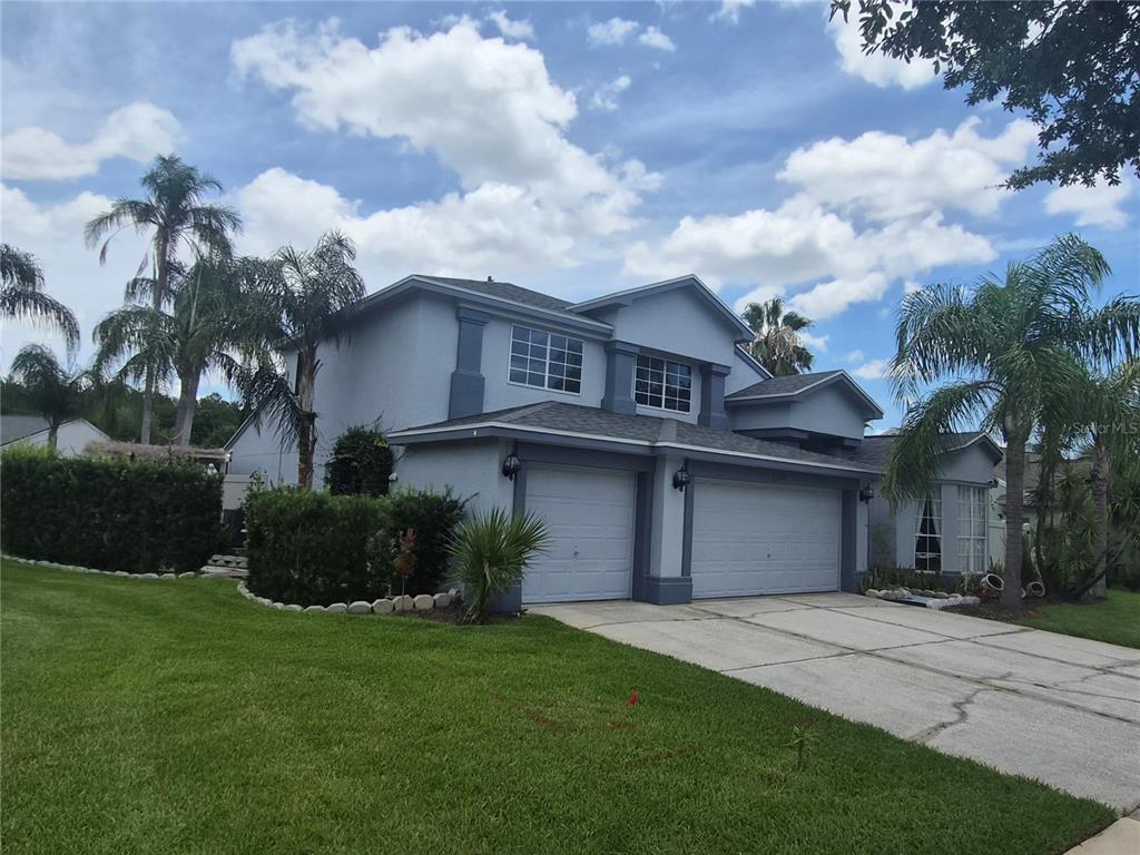 A two-story house with a gray exterior, two garage doors, and palm trees in front — 3244 AMACA CIRCLE, ORLANDO, FL