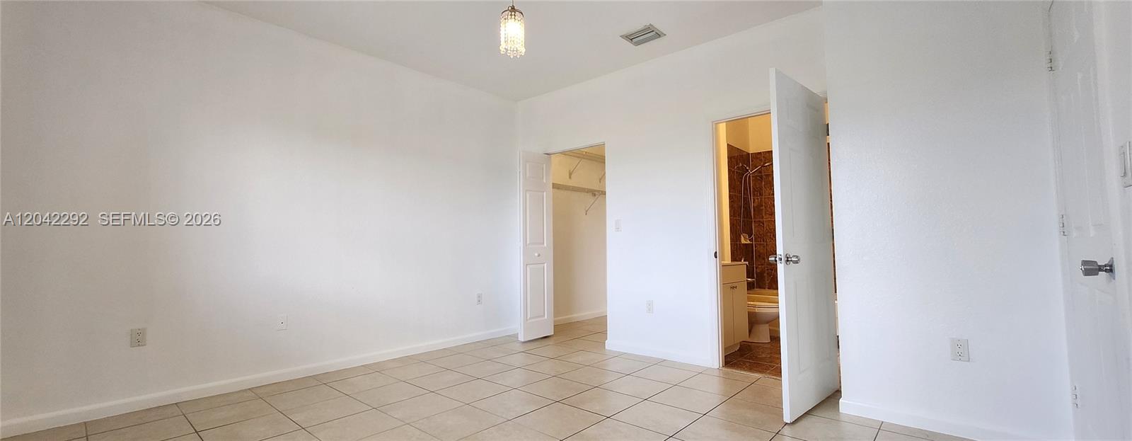 A room with white walls, tile flooring, a walk-in closet, and an attached bathroom — 10949 SW 181 TE # 0, Miami FL 33157, MIAMI, FL