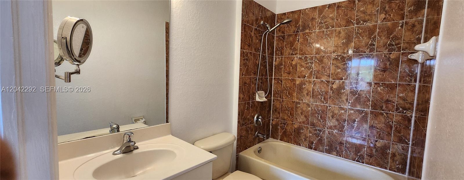 A bathroom features a vanity, a toilet, and a bathtub with brown tiled walls — 10949 SW 181 TE # 0, Miami FL 33157, MIAMI, FL