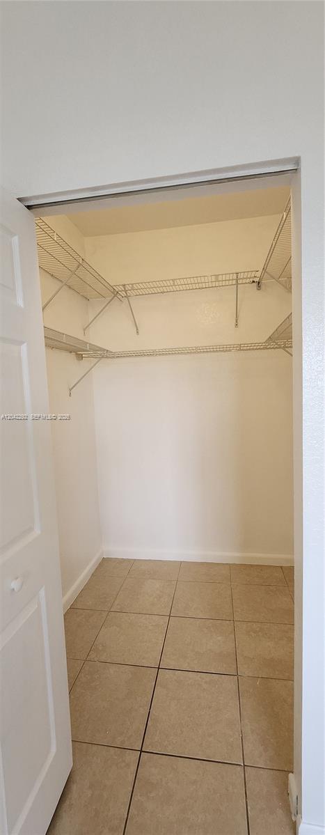 A walk-in closet features white wire shelving, beige tile flooring, and a white door — 10949 SW 181 TE # 0, Miami FL 33157, MIAMI, FL