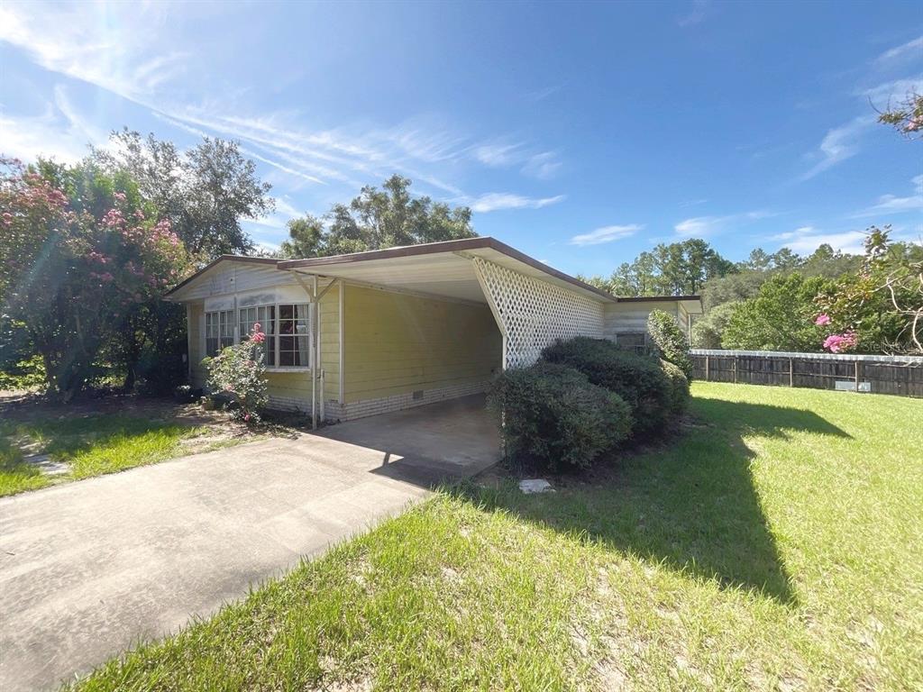 A single-story house with yellow siding, a concrete driveway, and an attached carport — 12830 SE 7TH STREET, SILVER SPRINGS, FL