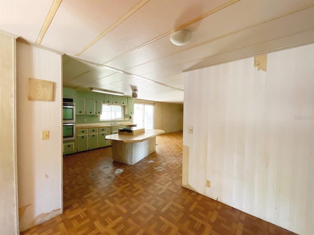 A kitchen with green cabinets, a central island, and patterned flooring in a mobile home — 12830 SE 7TH STREET, SILVER SPRINGS, FL
