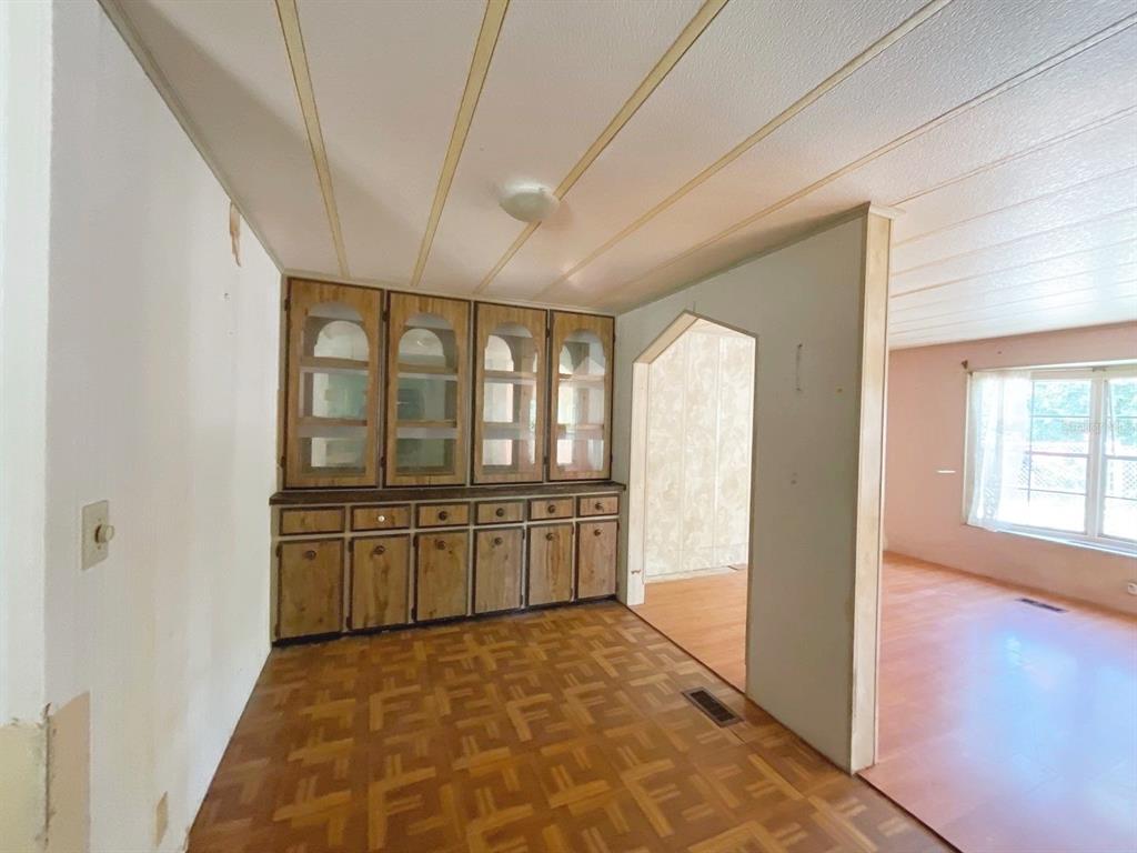 A dining area features wood cabinetry, parquet flooring, and an arched doorway leading to another room — 12830 SE 7TH STREET, SILVER SPRINGS, FL