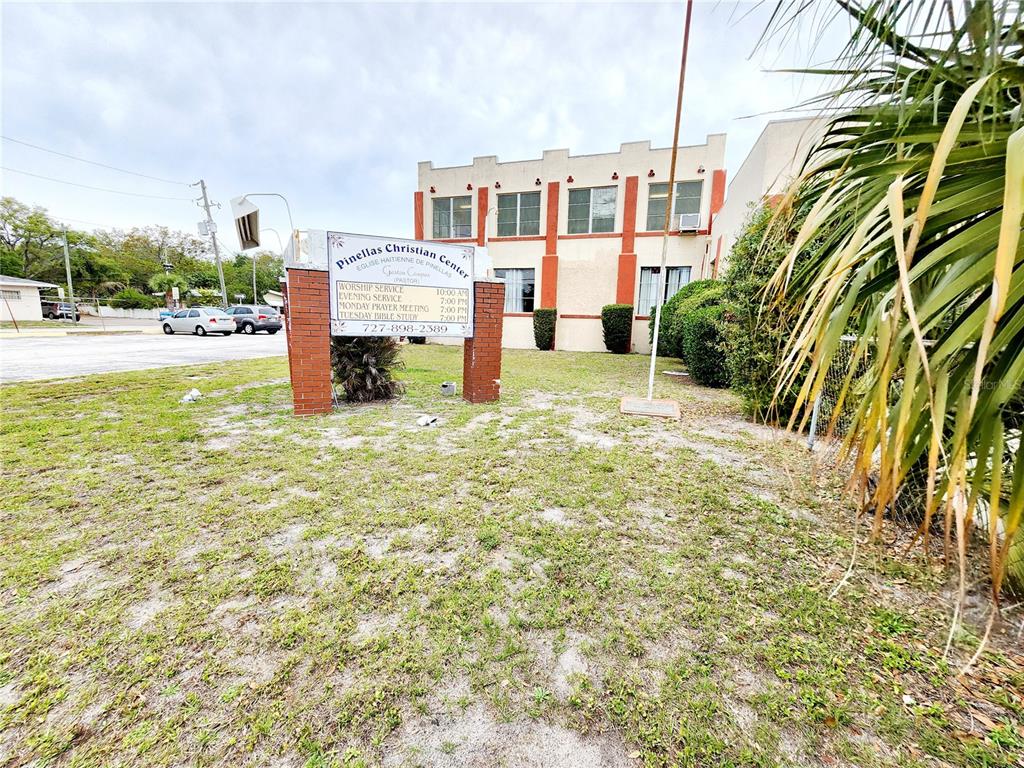 A beige, single-story commercial building with red accents features a central arched entrance — 1315 9TH AVENUE N, ST PETERSBURG, FL