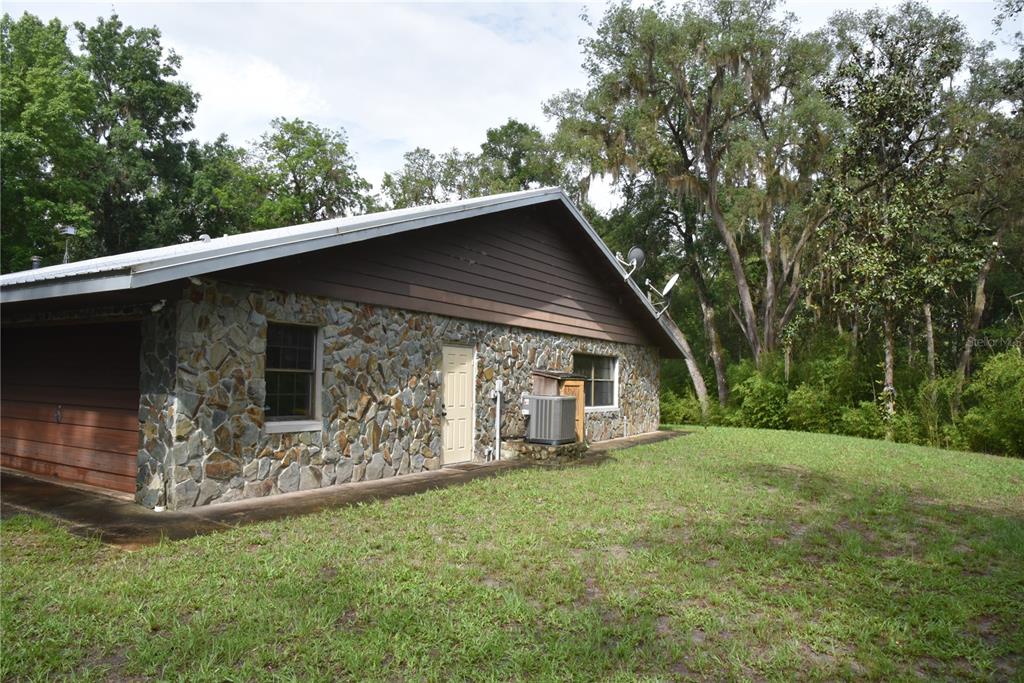 A single-story house with a stone facade, brown siding, and a garage in a wooded area — 8650 NW 136TH AVENUE, CHIEFLAND, FL