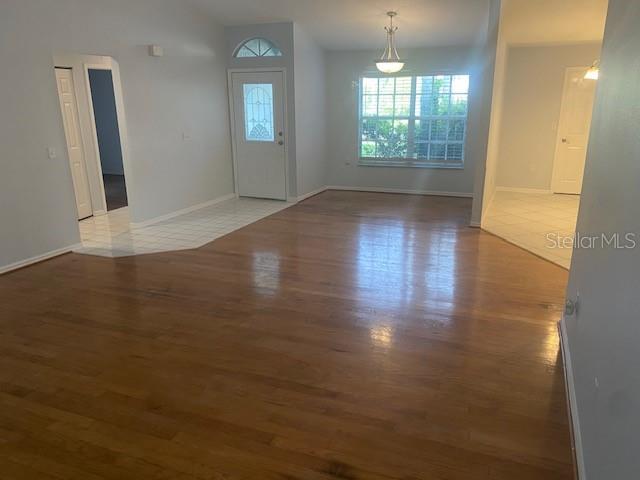 An interior view shows a living area with hardwood floors, a front door, and tile — 7050 WOODIBIS DRIVE, NEW PORT RICHEY, FL
