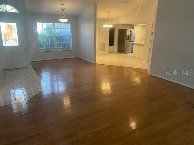 An open-concept living area features hardwood floors, a tiled entryway, and an adjacent kitchen — 7050 WOODIBIS DRIVE, NEW PORT RICHEY, FL