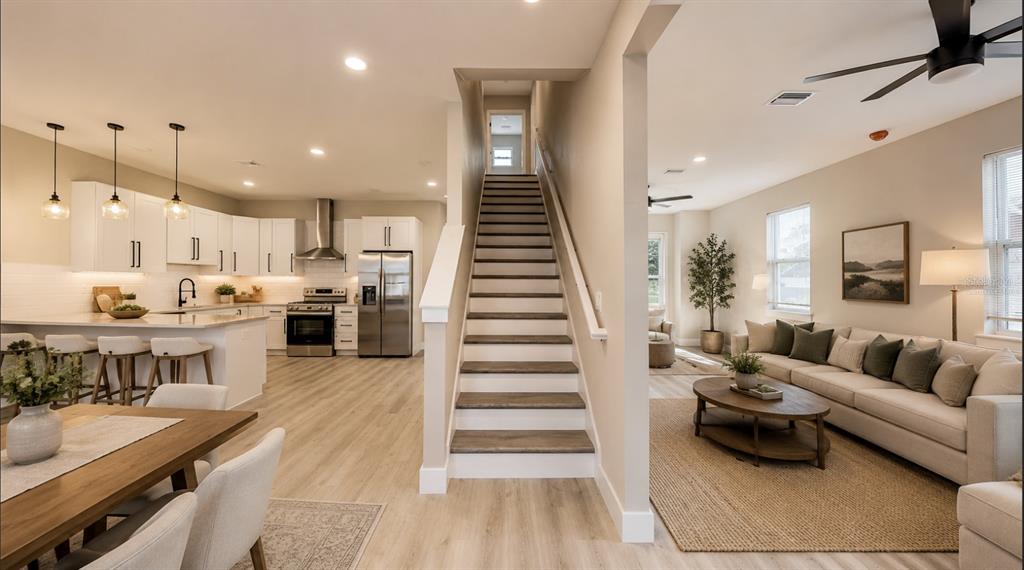 An open-concept interior features a kitchen, a central staircase, and a living room with furniture — 5112 3RD AVENUE N, ST PETERSBURG, FL