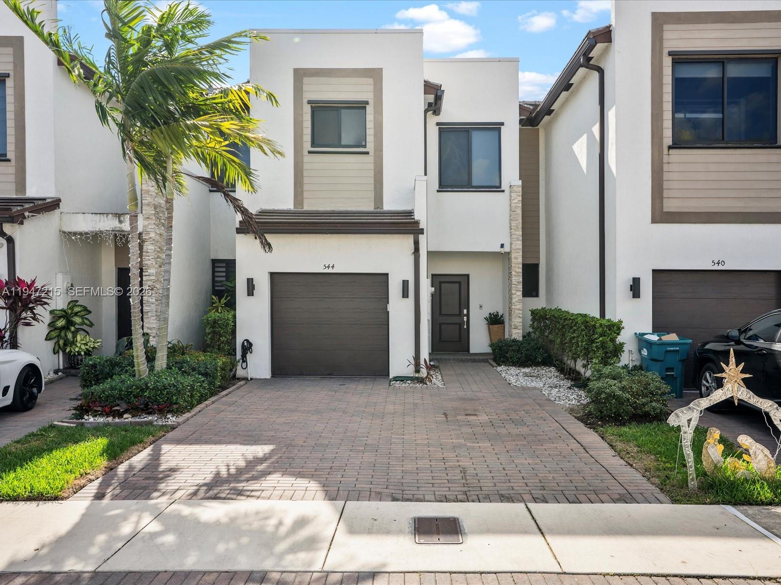 A two-story townhouse features a paved driveway, a single-car garage, and a front entrance — 544 NE 206th Ln, Miami FL 33179, MIAMI, FL