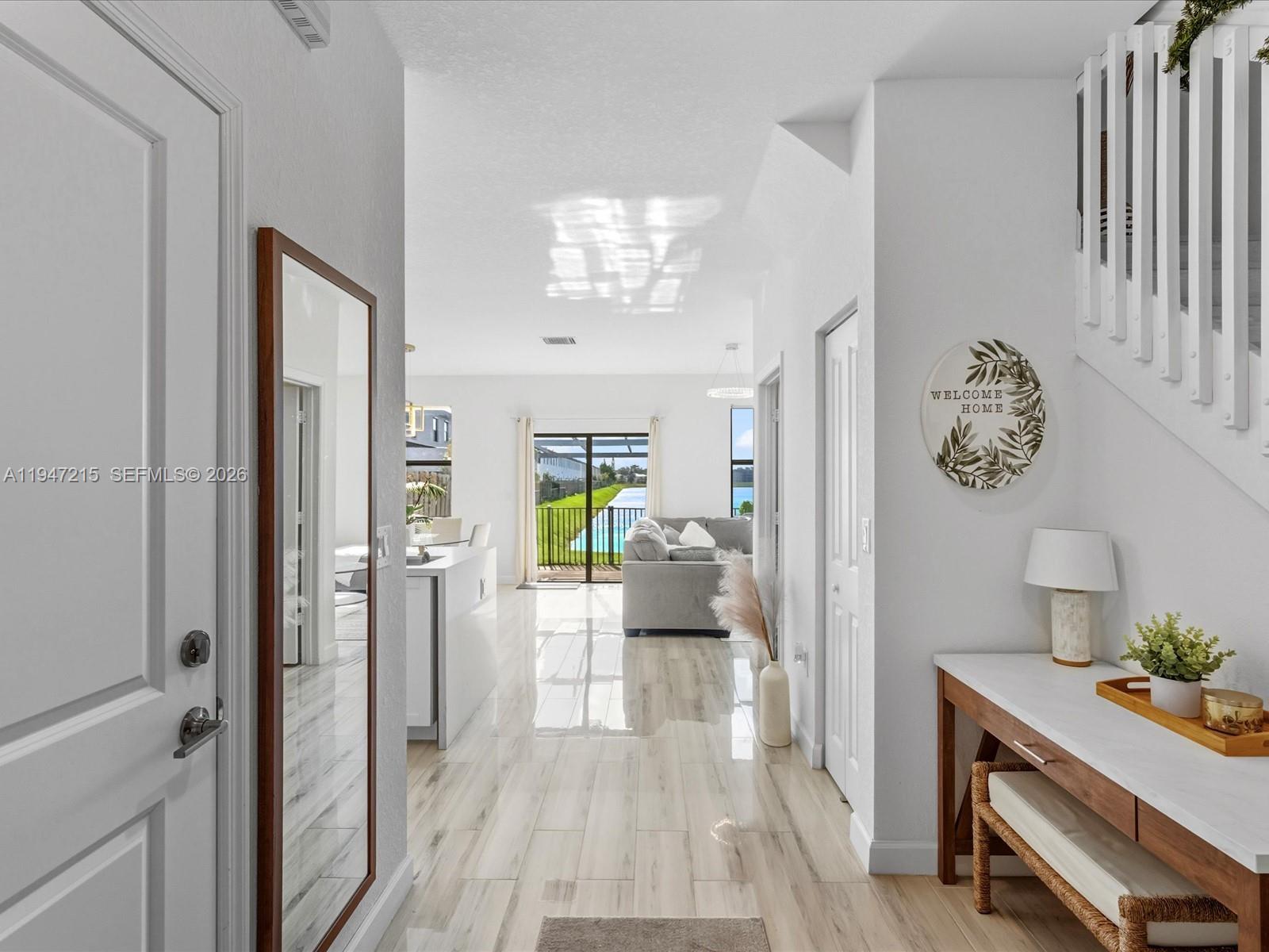 A bright entryway leads to an open living area with tile floors and a water view — 544 NE 206th Ln, Miami FL 33179, MIAMI, FL