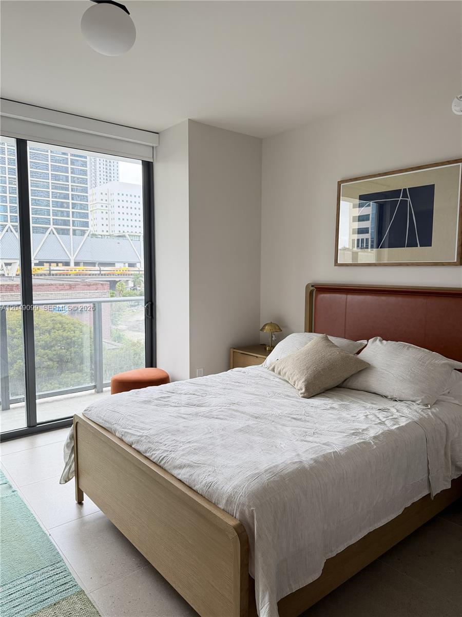 A bedroom features a wooden bed frame, a leather headboard, and a floor-to-ceiling window — 11 NE 6th St # 515, Miami FL 33132, MIAMI, FL